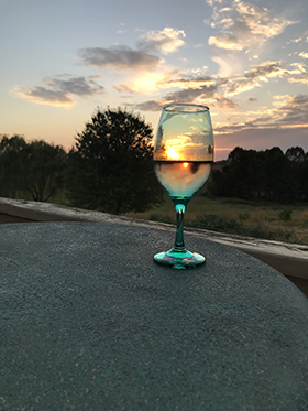 A glass of wine on the deck with the most beautiful sunsets.